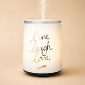 White LIVE LAUGH LOVE ultrasonic diffuser with mist on a pastel background